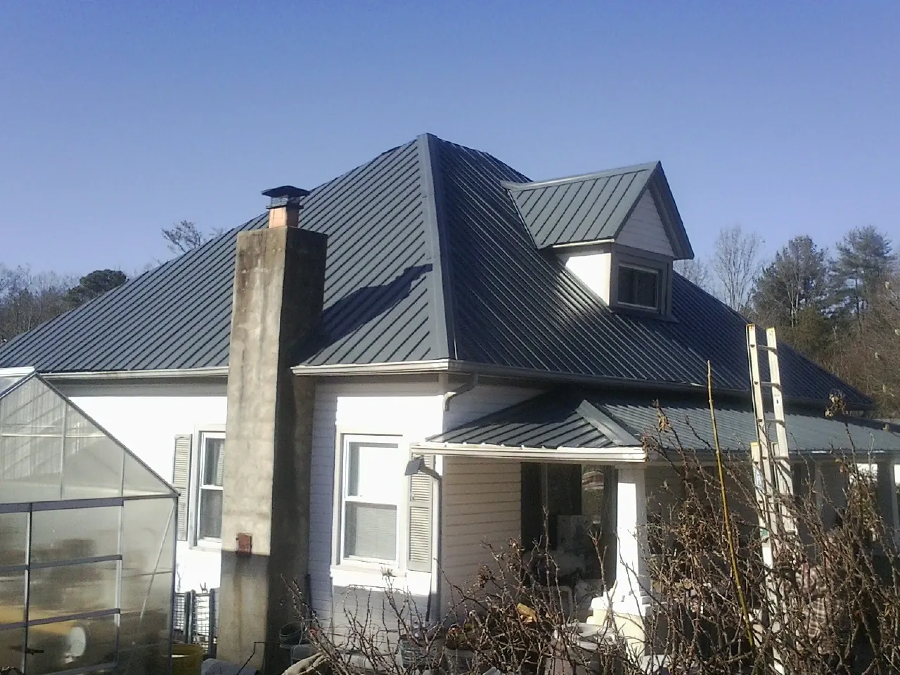 Dark blue standing seam metal roof on a white farmhouse with dormer — Slate & Tile Roof Repair by Roofing Brothers in Hackleburg