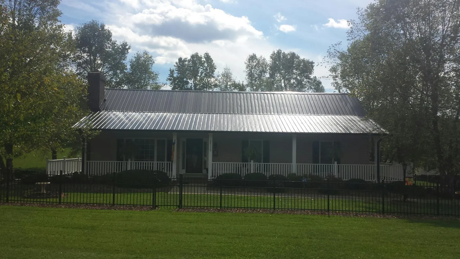 Gray metal roof on a brick ranch with a full width front porch — Gutter Guard Installation work by our crew in Hackleburg