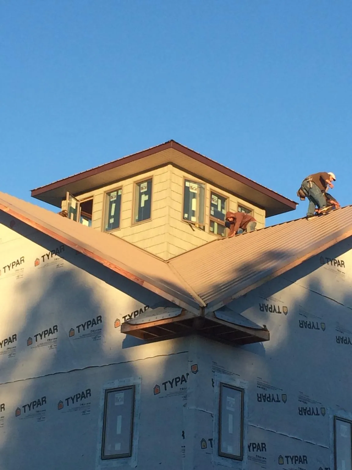 Roofers working around a rooftop cupola on a new metal roof at sunset — Roof Waterproofing in Hackleburg by Roofing Brothers